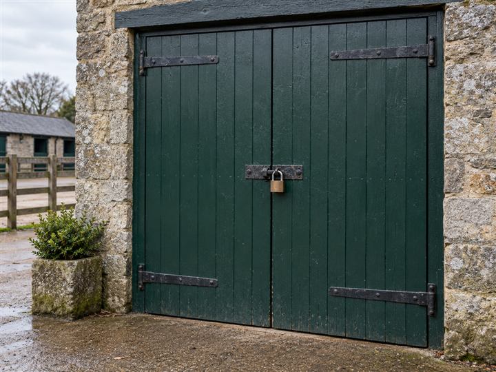 Closed green tack-room doors secured with a padlock and hasp